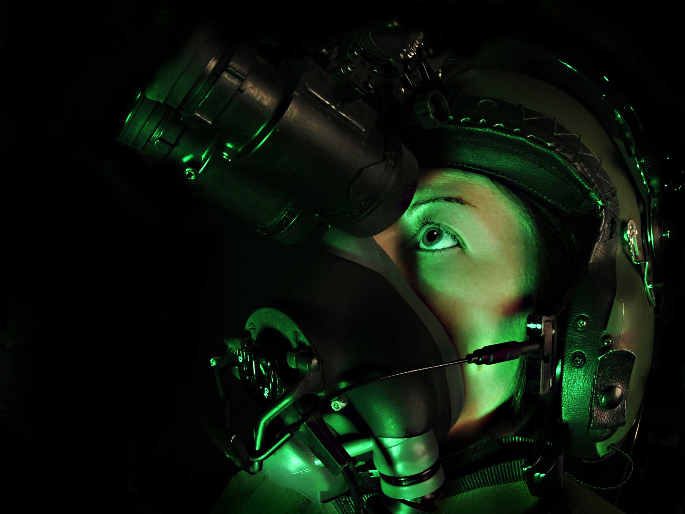 Image shows aviator wearing specialist helmet with binocular and light attachment.